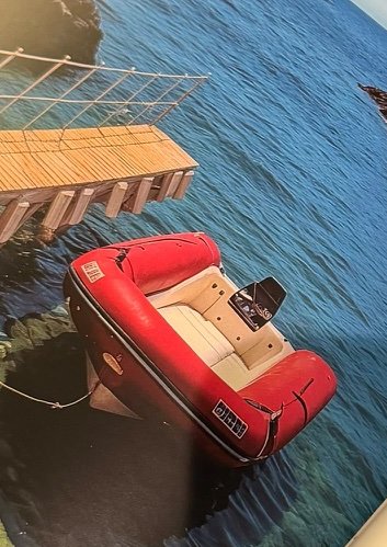 Inside the book: A red boat in a rocky cove on the Mediterranean